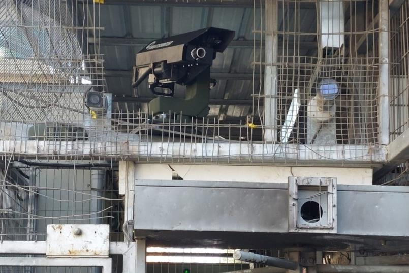 Figure 2. Installation of a new remote-controlled weapons system at the Al-Shuhada Street checkpoint in Hebron. Other surveillance cameras are also visible. Photo credit: Youth Against Settlements / Issa Amro